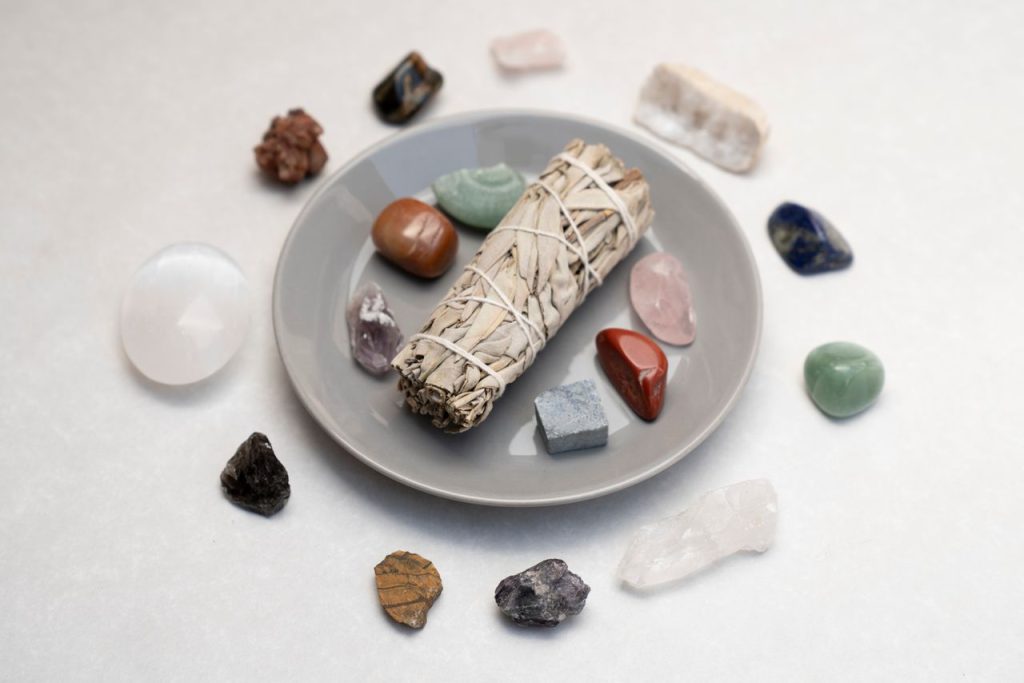 Ceramic plate with sage smudge stick and healing crystals for spiritual rituals.